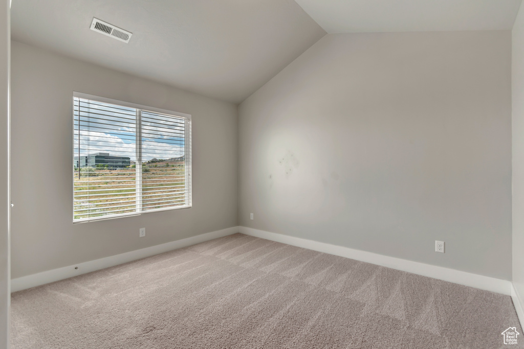 Spare room with light carpet, lofted ceiling, and baseboards