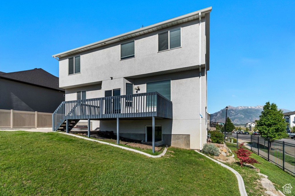 Rear view of property with a deck with mountain view, stucco siding, and stairs