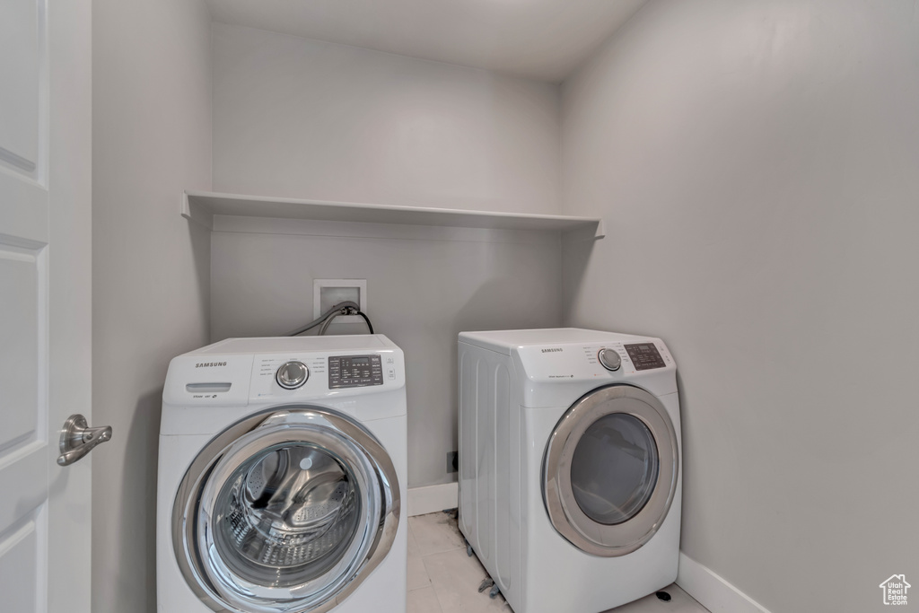 Washroom with washer and dryer, baseboards, and light tile patterned floors
