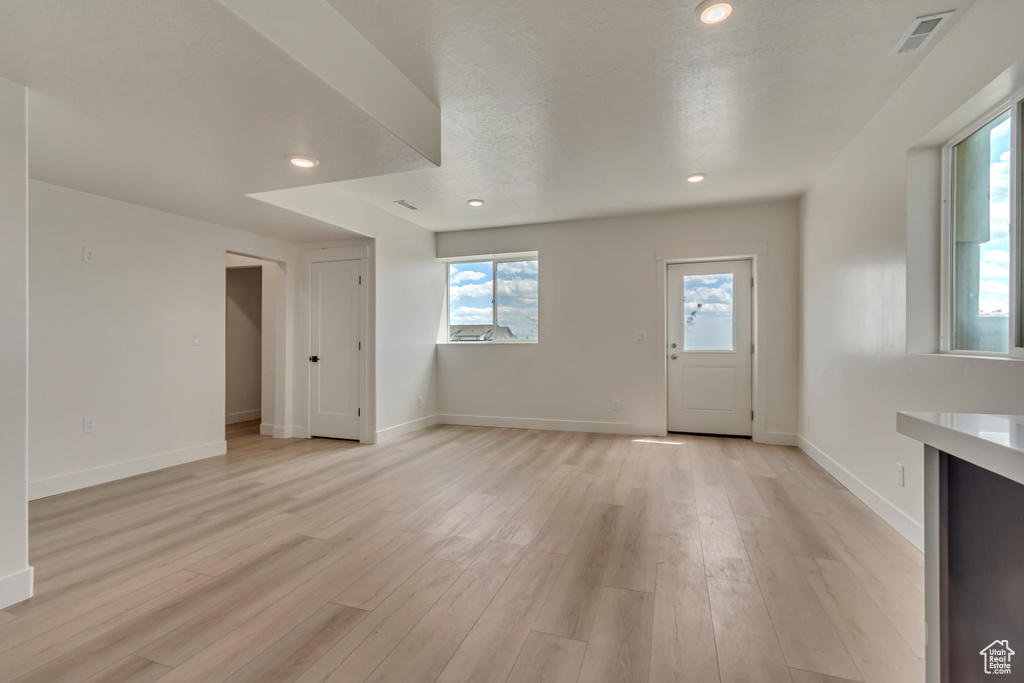 Unfurnished living room featuring light wood-style floors, baseboards, and recessed lighting