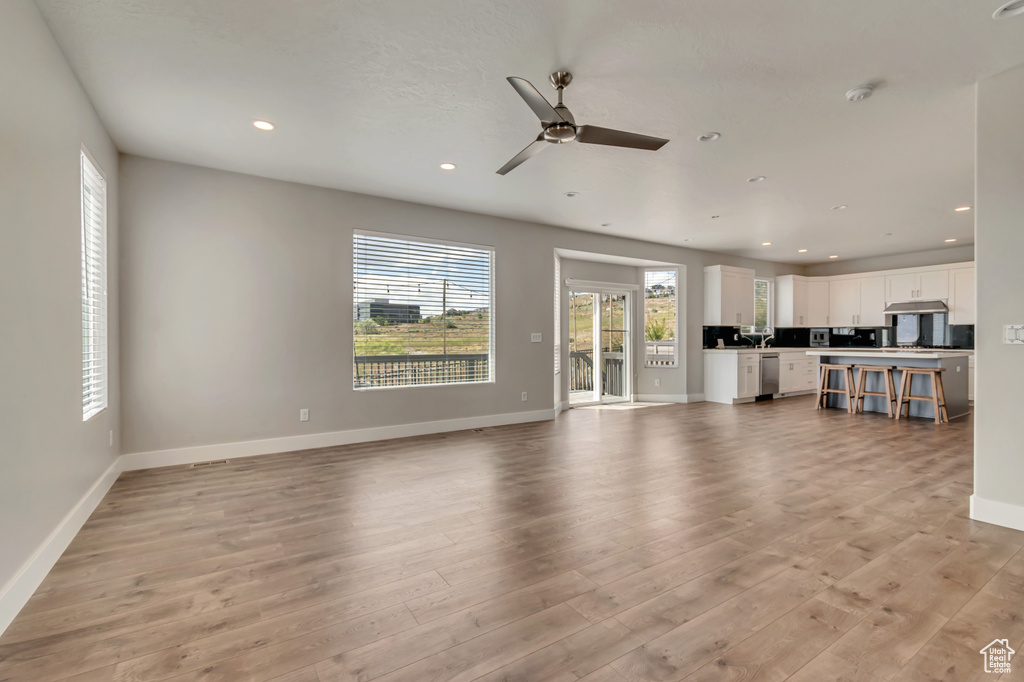 Unfurnished living room with light wood-type flooring, recessed lighting, baseboards, and ceiling fan
