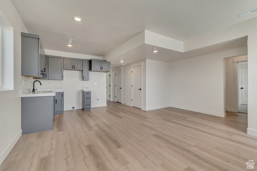 Unfurnished living room featuring baseboards, recessed lighting, light wood-type flooring, and a sink