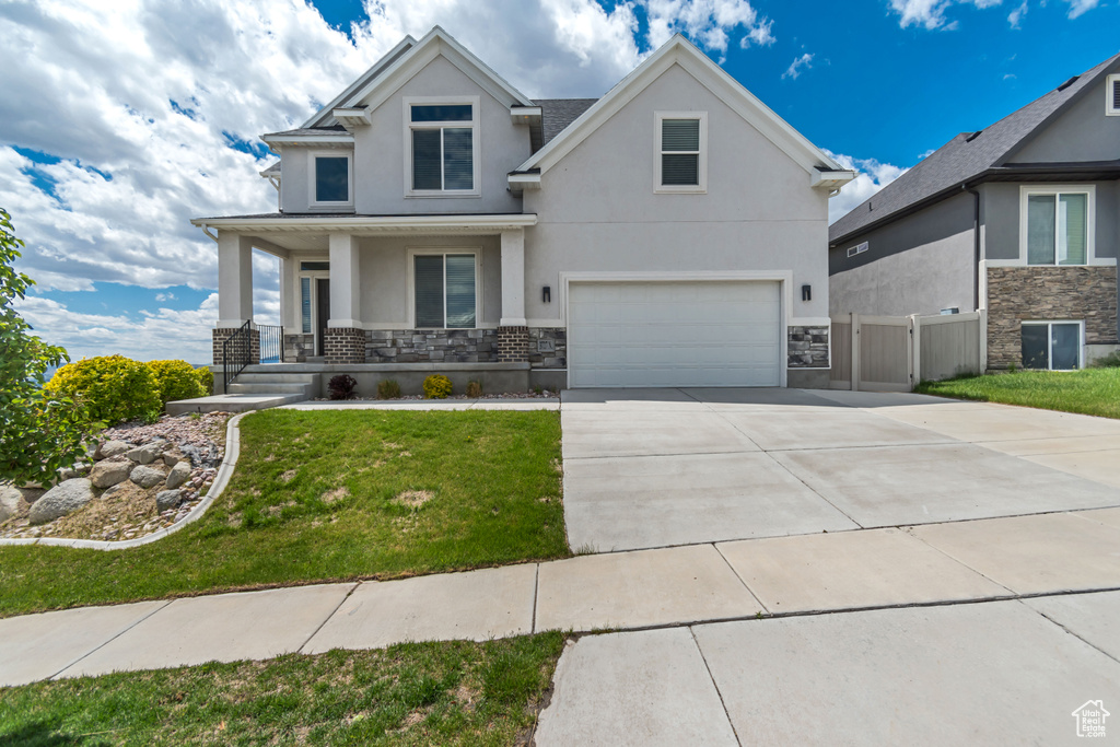 View of front facade featuring stucco siding, an attached garage, a porch, and stone siding
