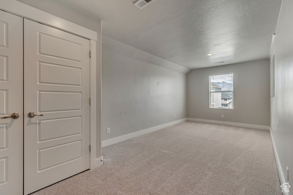 Spare room with a textured ceiling, baseboards, and carpet