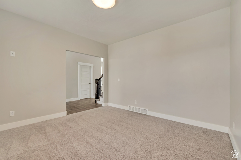 Carpeted spare room featuring baseboards and stairs