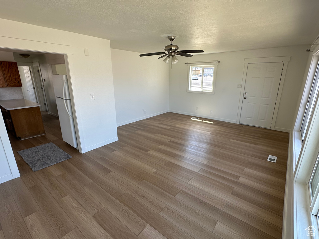 Unfurnished living room featuring wood finished floors, a ceiling fan, and baseboards