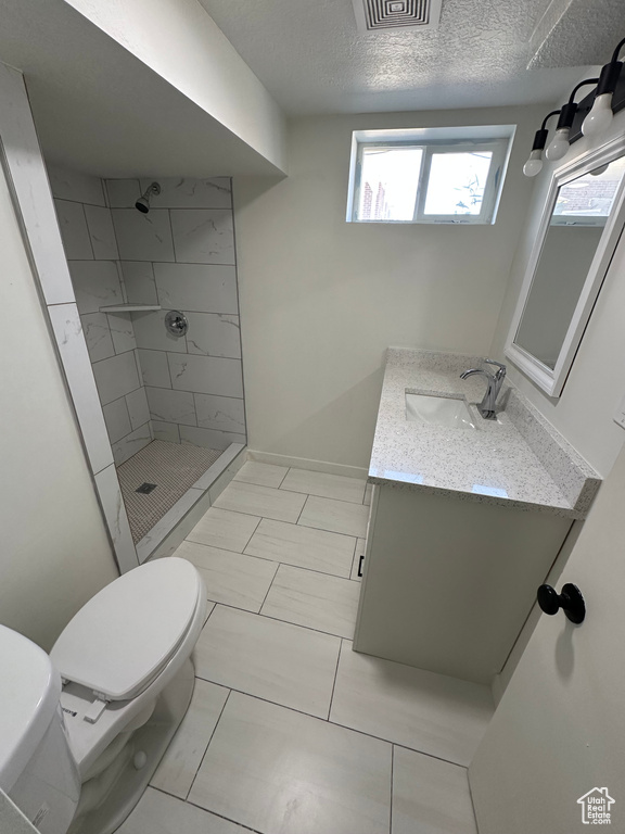 Full bath featuring a stall shower, vanity, toilet, and a textured ceiling