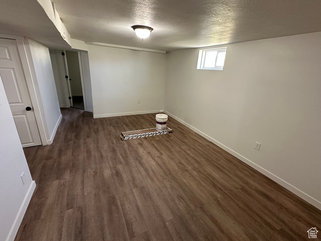 Below grade area with dark wood finished floors, a textured ceiling, and baseboards