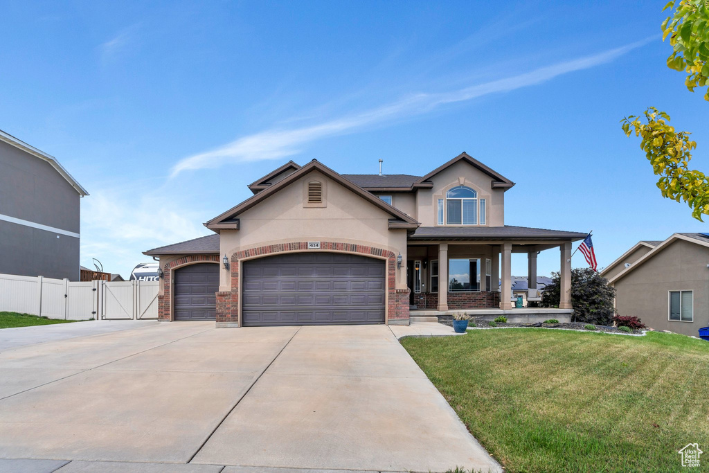 View of front of house featuring a gate, brick siding, a porch, stucco siding, and driveway