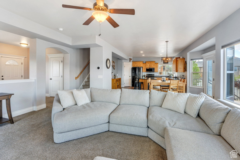 Living area featuring stairway, baseboards, light colored carpet, a ceiling fan, and recessed lighting