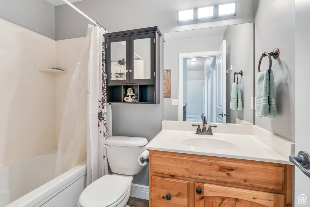 Bathroom featuring toilet, vanity, and shower / bath combination with curtain