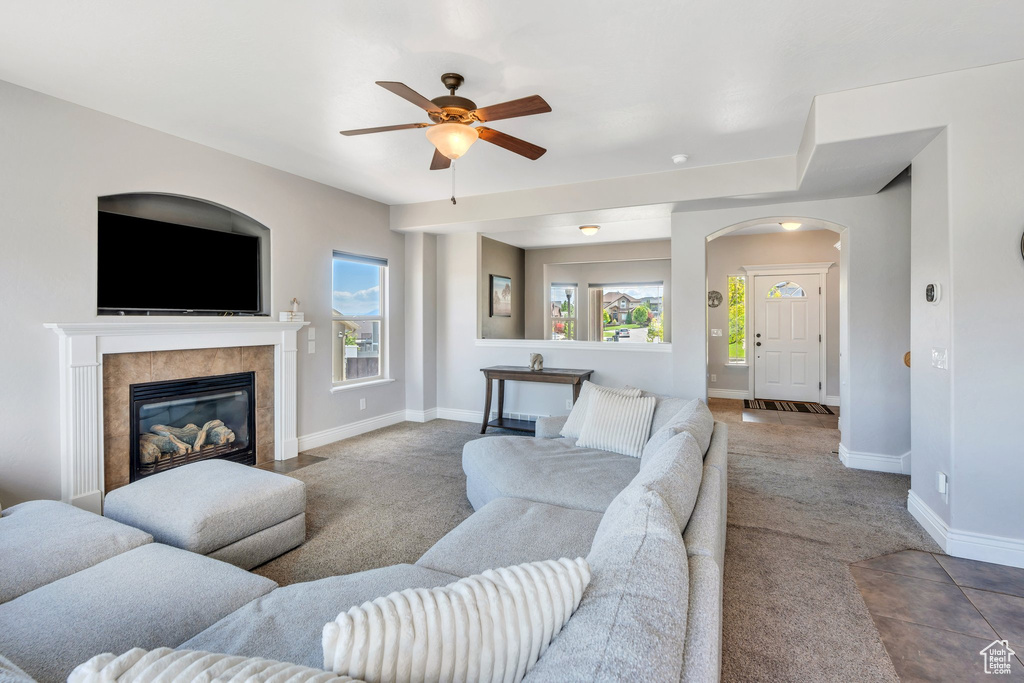 Living area featuring carpet flooring, ceiling fan, arched walkways, baseboards, and a fireplace