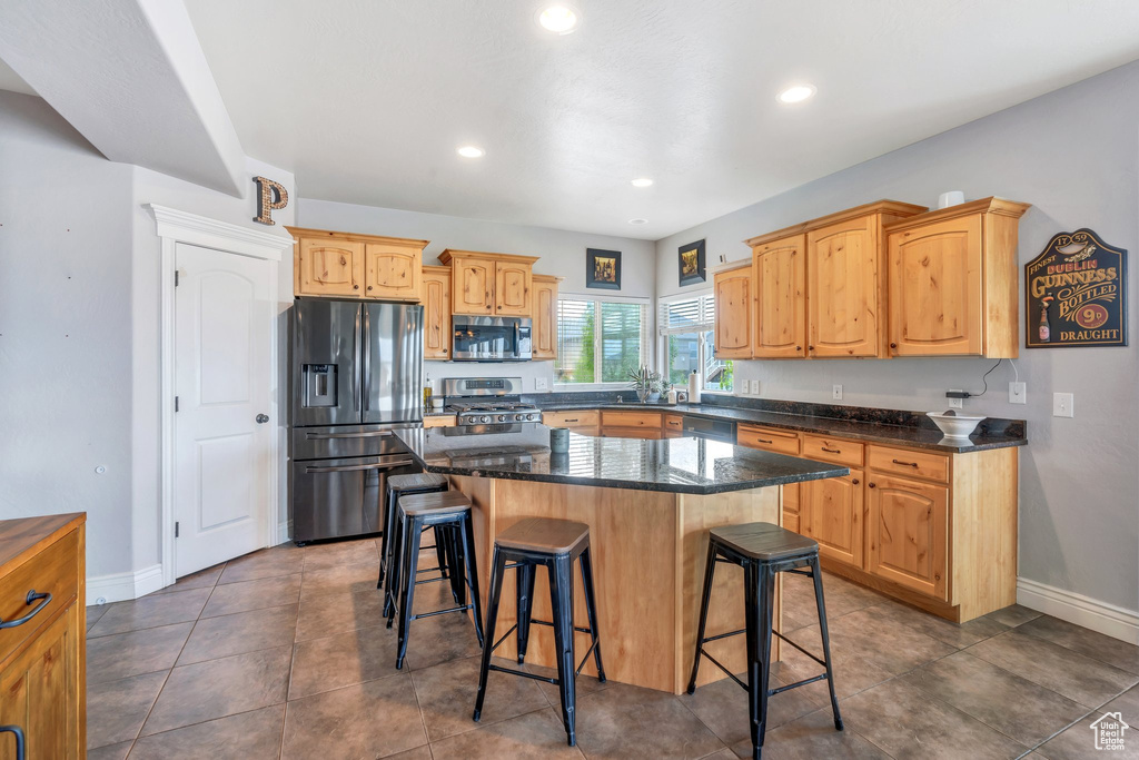 Kitchen with appliances with stainless steel finishes, a breakfast bar, baseboards, recessed lighting, and a center island