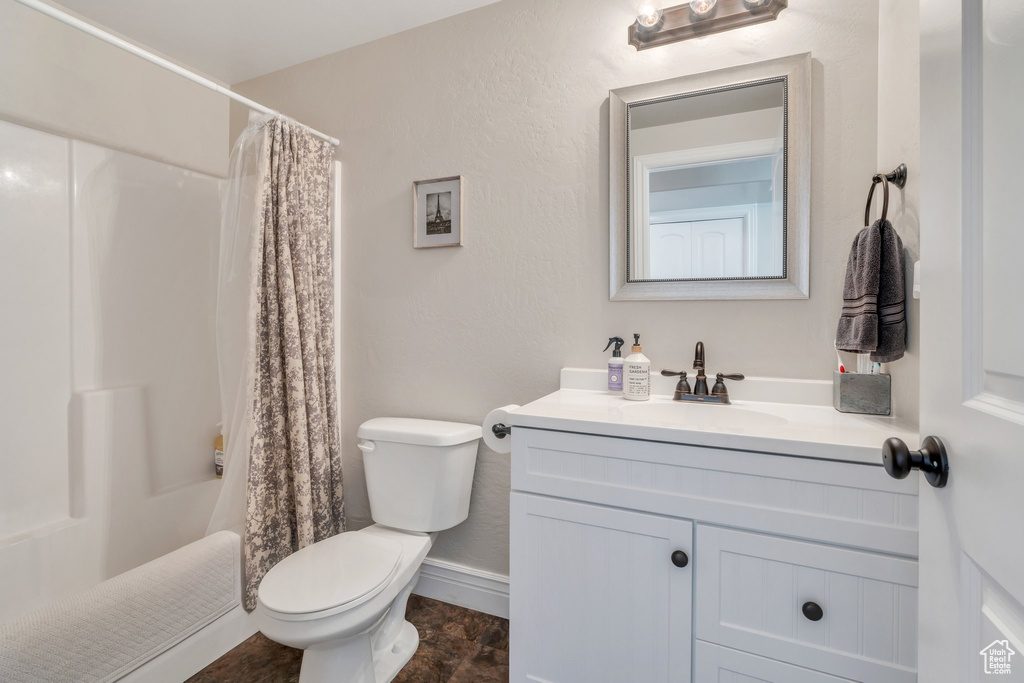 Full bathroom featuring toilet, vanity, and baseboards