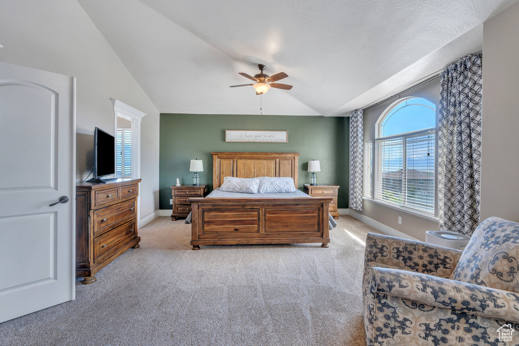 Bedroom with vaulted ceiling, light carpet, baseboards, and a ceiling fan