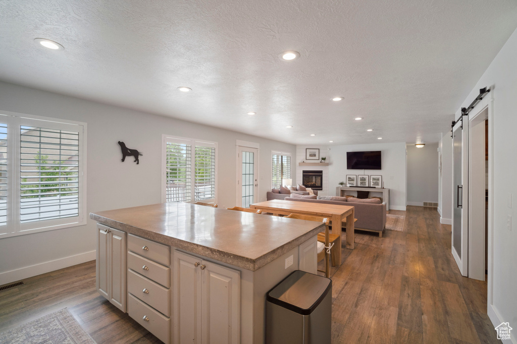 Kitchen with a kitchen island, baseboards, dark wood-style flooring, a barn door, and a fireplace