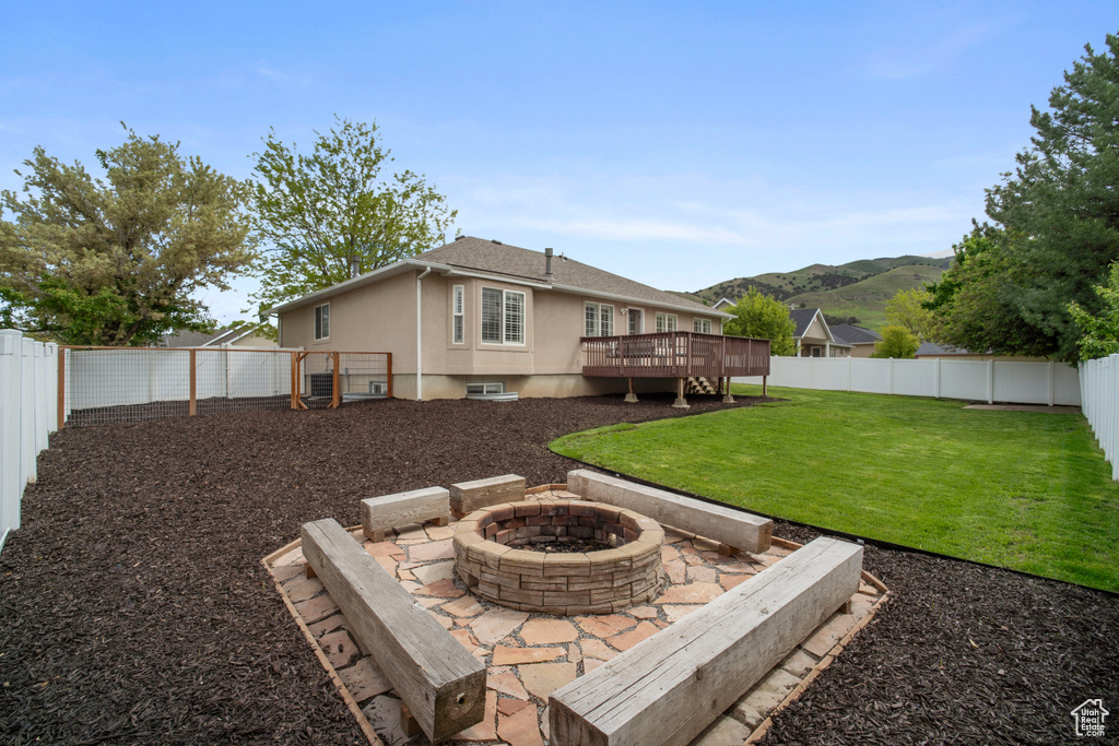 Back of property featuring an outdoor fire pit, a deck with mountain view, and stucco siding