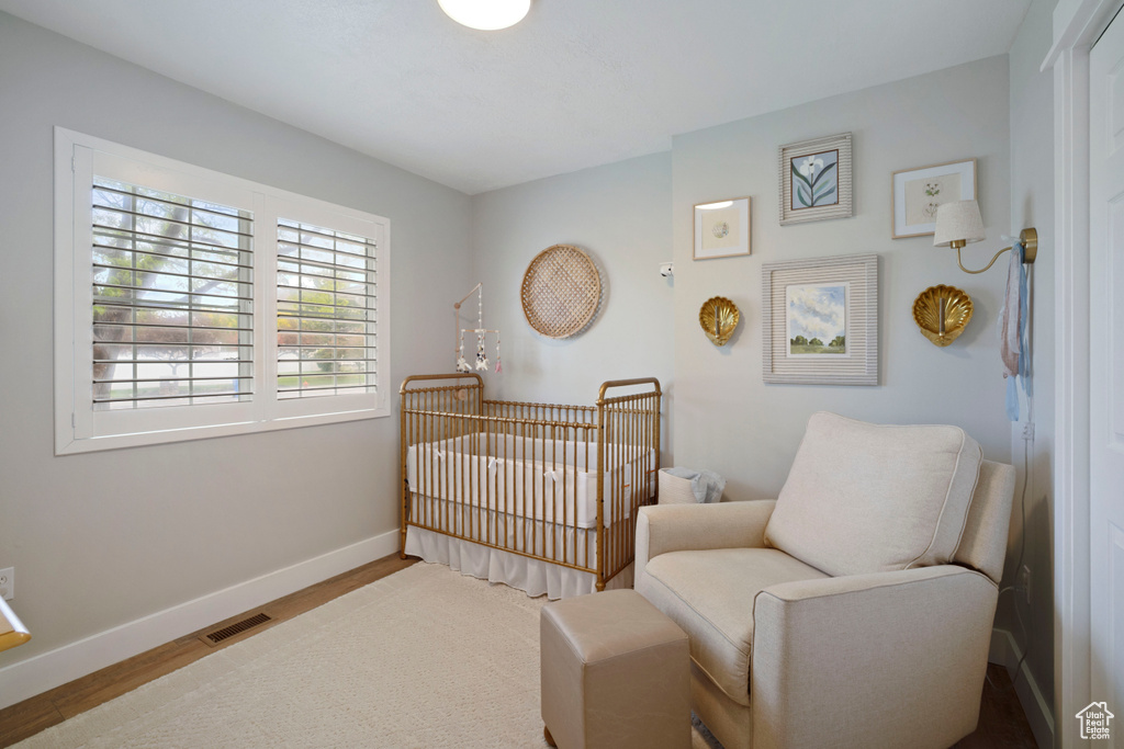 Bedroom featuring a crib, baseboards, and wood finished floors