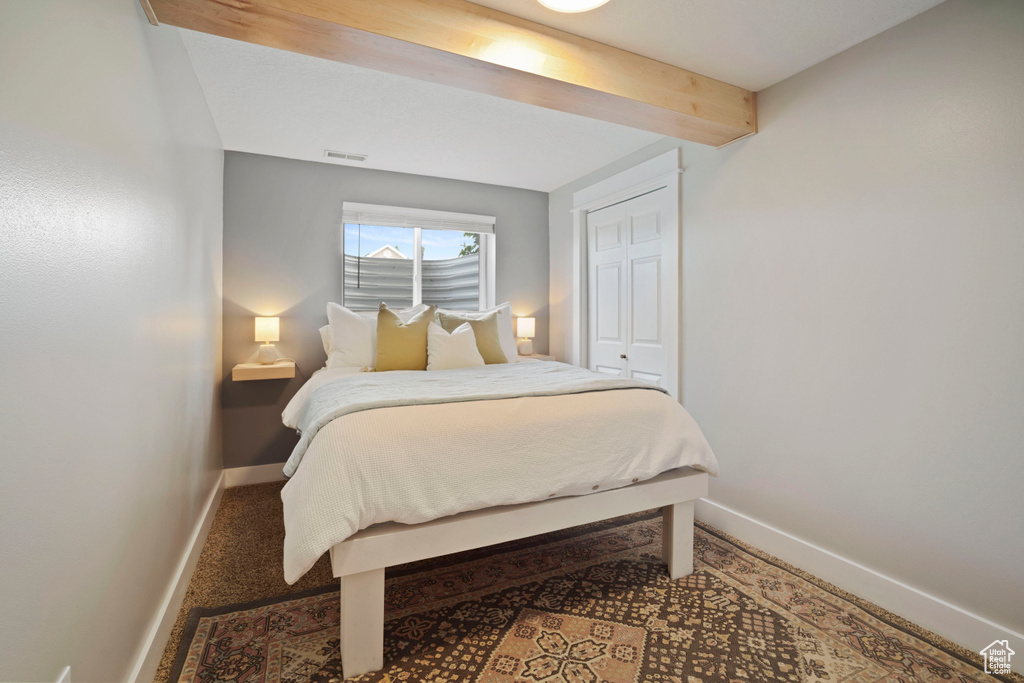 Bedroom featuring baseboards, beam ceiling, and a closet