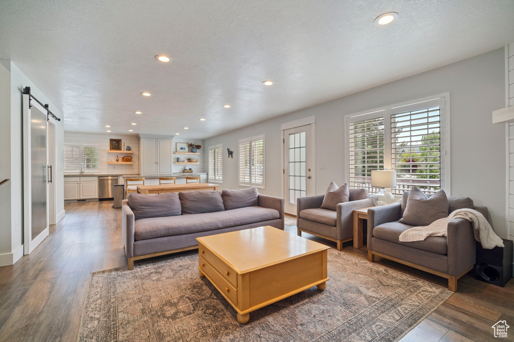 Living room with healthy amount of natural light, recessed lighting, a barn door, and dark wood finished floors
