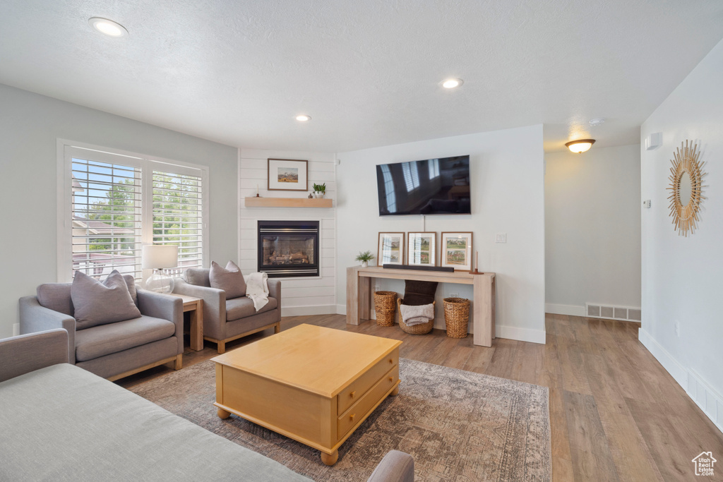Living area featuring wood finished floors, a large fireplace, recessed lighting, and baseboards