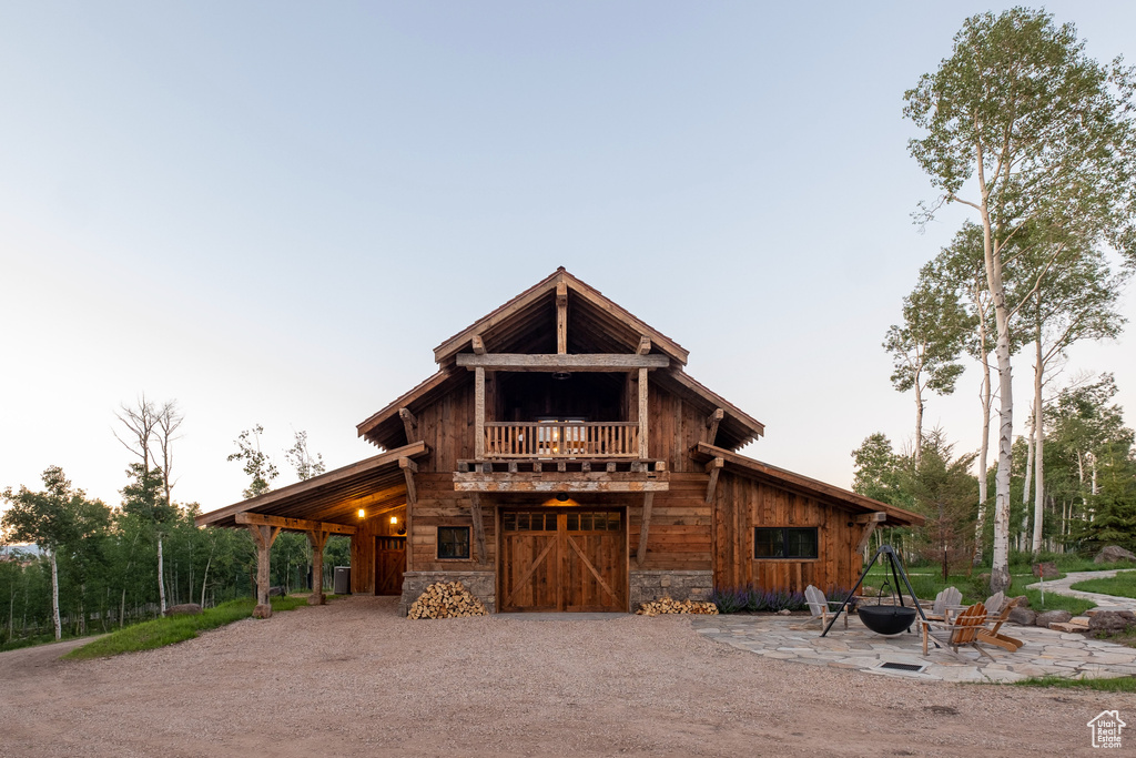 View of front of house with dirt driveway, stone siding, and a barn