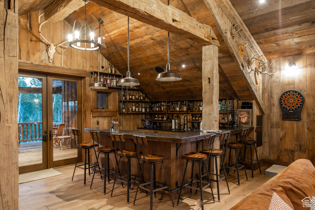 Indoor wet bar with wooden ceiling, french doors, wood walls, wood finished floors, and beam ceiling