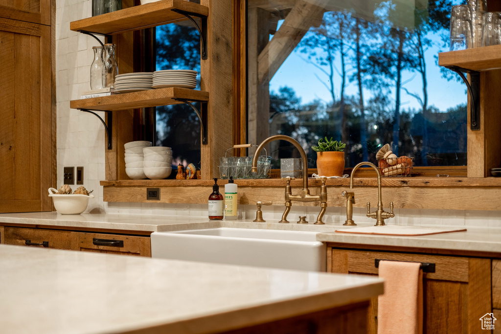 Kitchen with open shelves, decorative backsplash, light countertops, and a sink