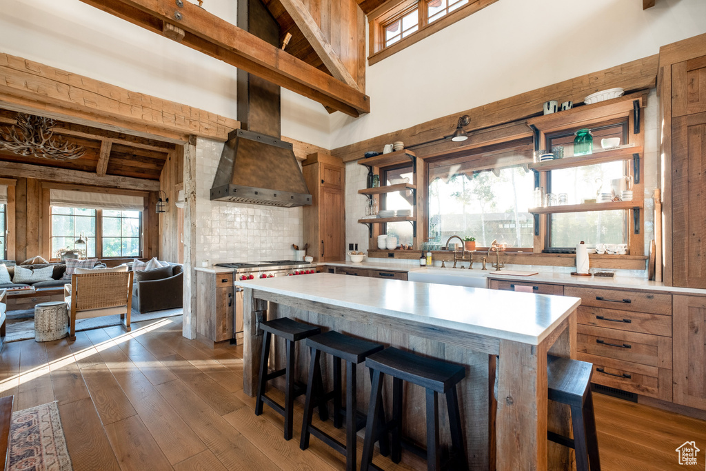 Kitchen featuring a sink, high vaulted ceiling, light countertops, dark wood-type flooring, and a breakfast bar area