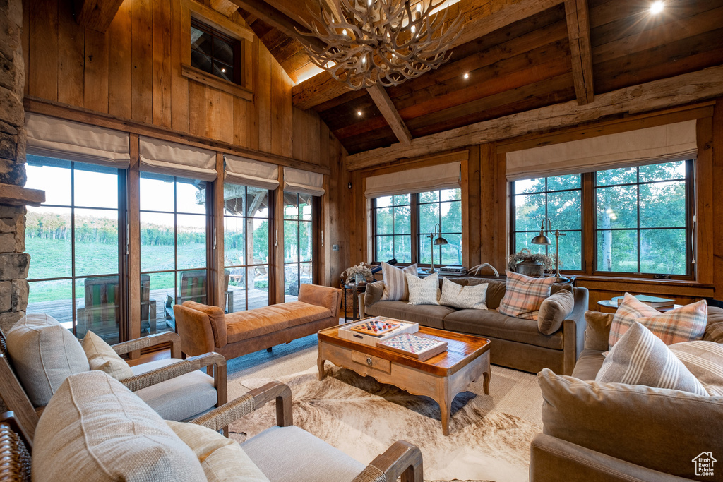 Living area featuring a chandelier, wood ceiling, beamed ceiling, plenty of natural light, and wood walls