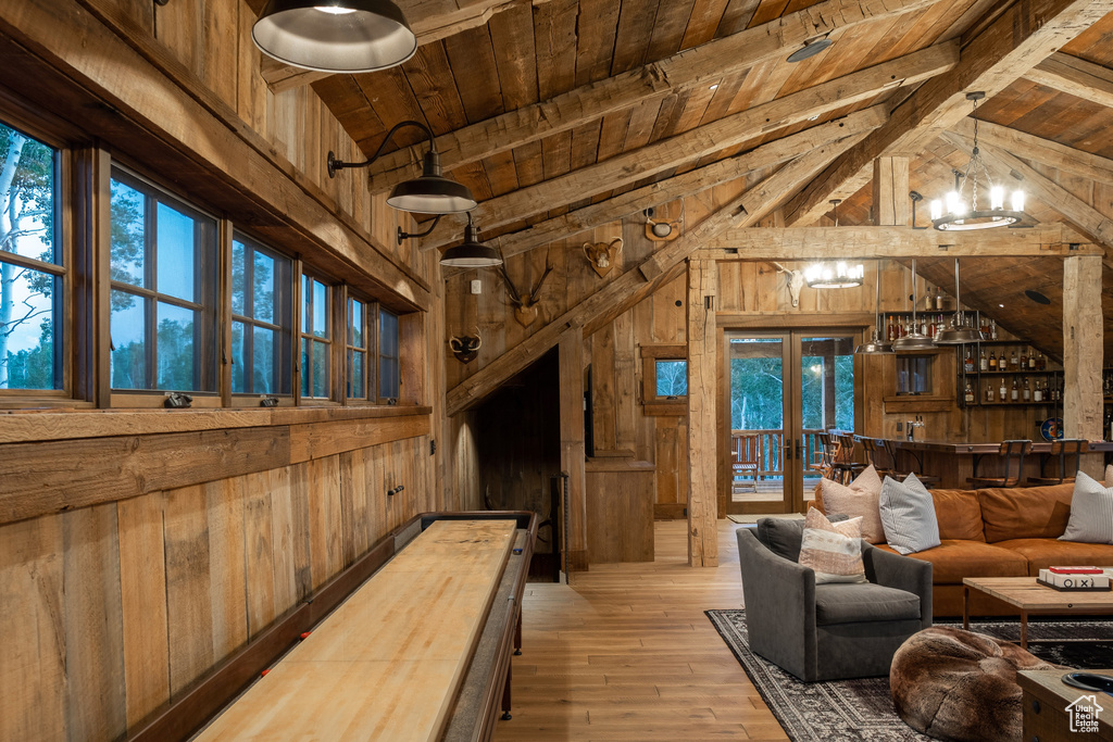 Living room with wooden walls, wood ceiling, a chandelier, hardwood / wood-style floors, and french doors
