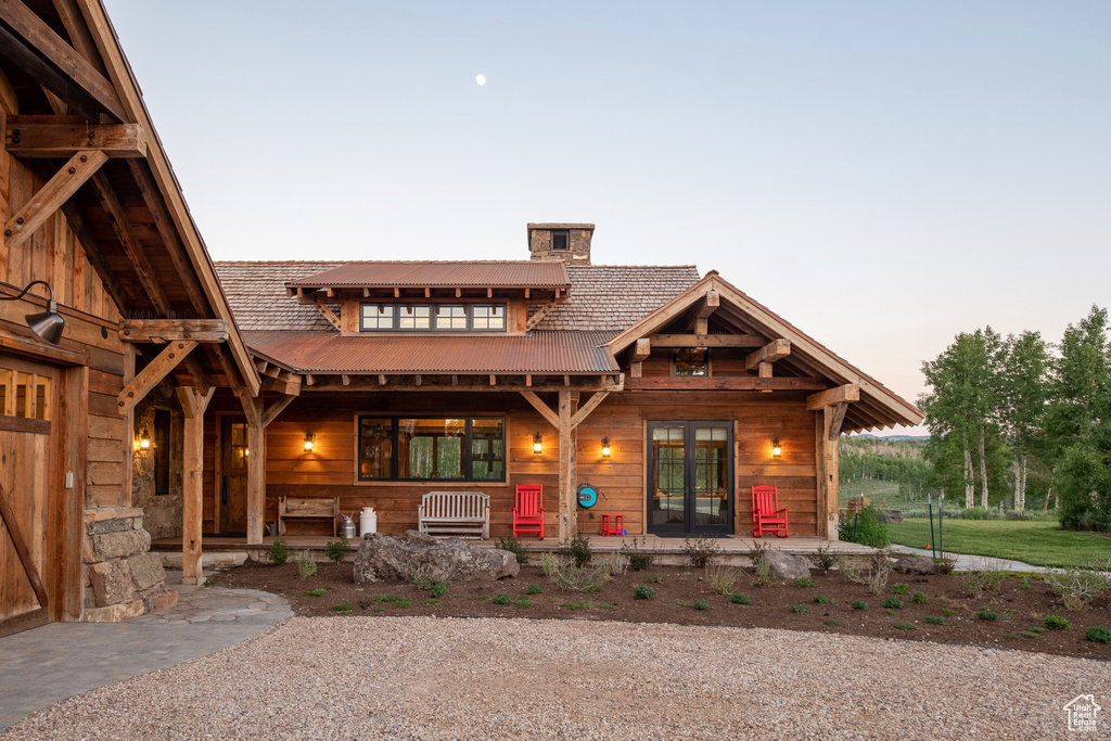Log home with a chimney, covered porch, and french doors