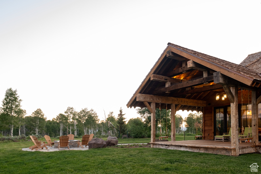 View of green lawn featuring a fire pit and a deck