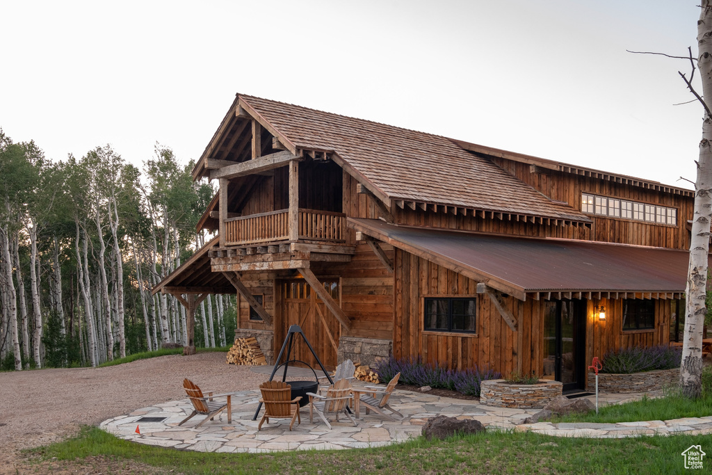 Rear view of house featuring a patio, a balcony, and board and batten siding