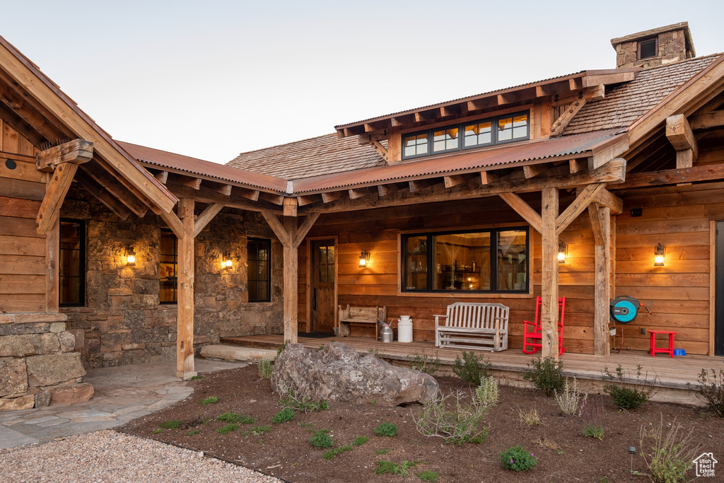 View of exterior entry featuring covered porch and stone siding