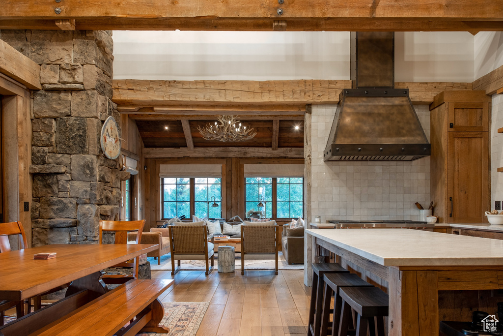 Kitchen featuring custom range hood, beamed ceiling, light wood-style flooring, light countertops, and stainless steel gas stovetop