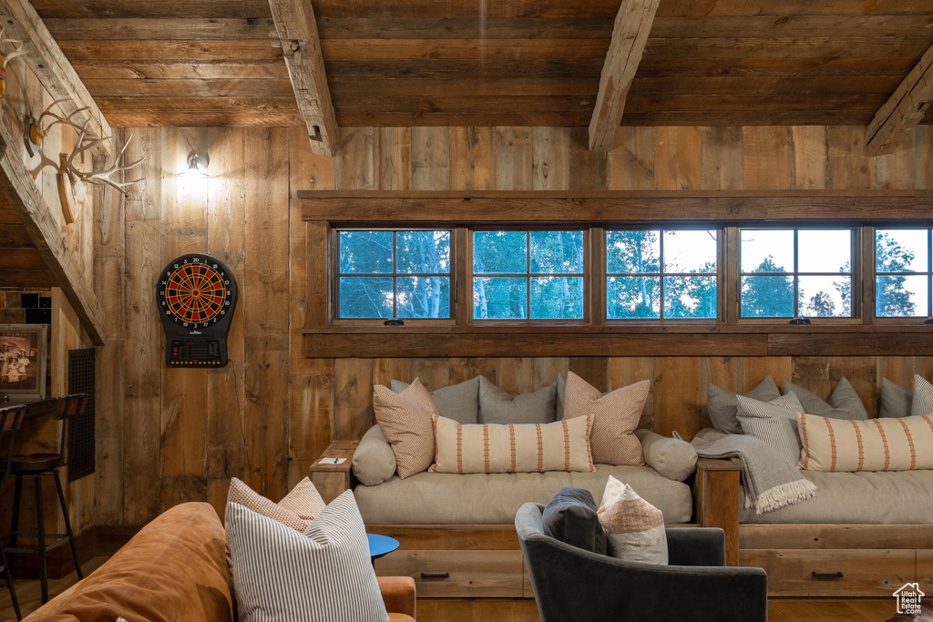Living area featuring wood ceiling with exposed beams, wooden walls, and wood finished floors