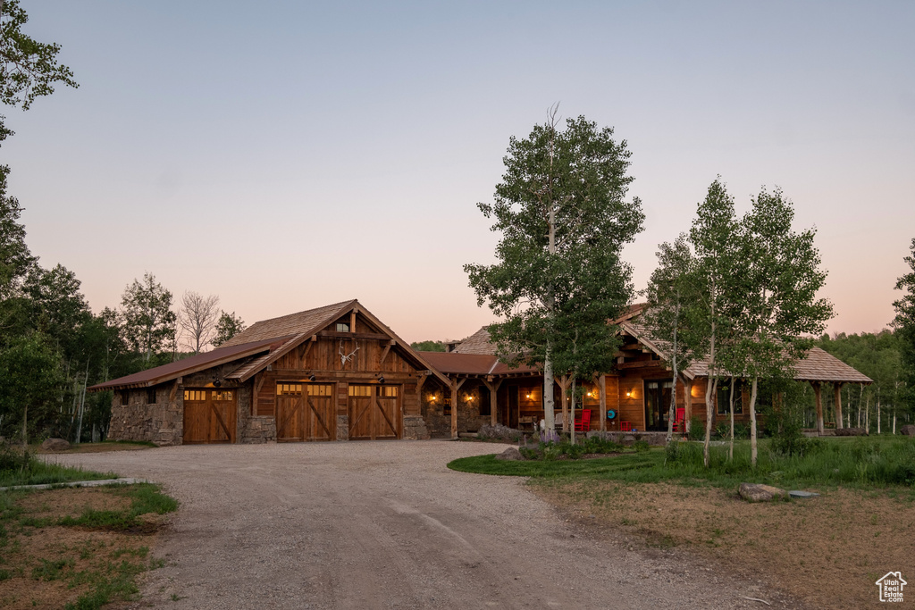 Rustic home featuring driveway, stone siding, and an attached garage
