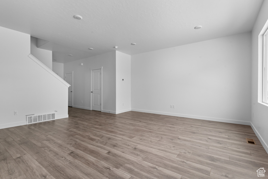Unfurnished living room featuring light wood-style floors and baseboards