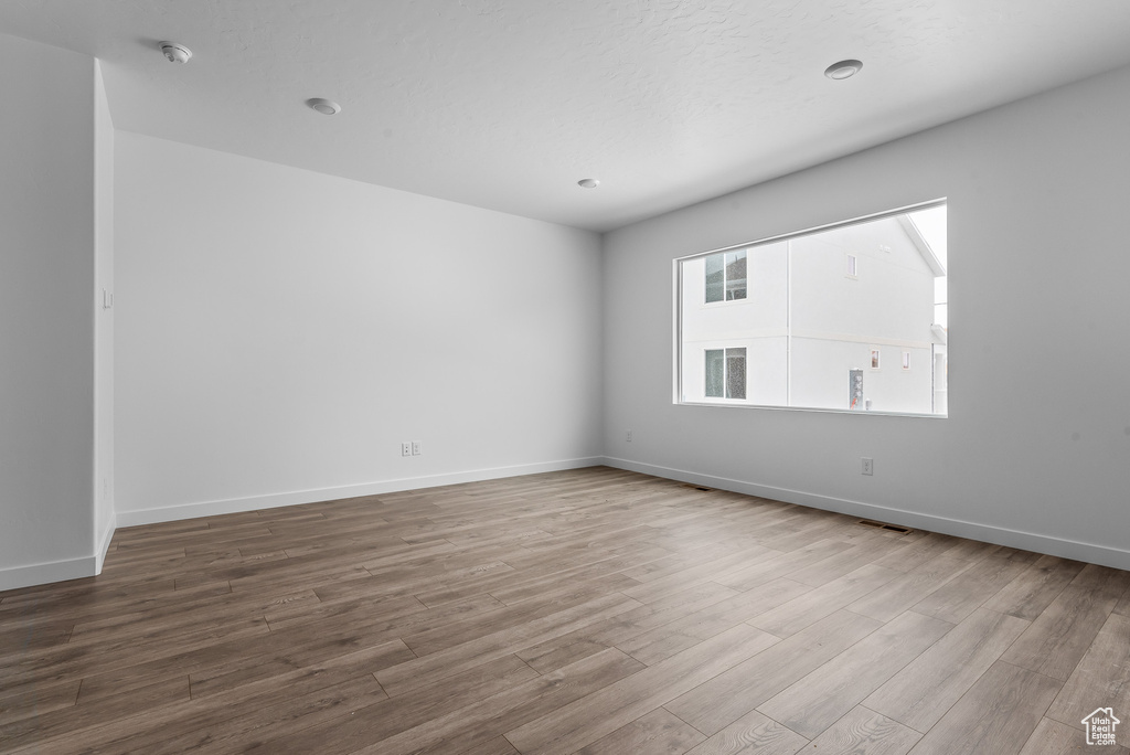 Empty room featuring wood finished floors, a smoke detector, and baseboards