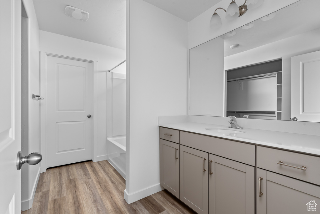 Full bath featuring vanity, wood finished floors, shower / tub combination, and baseboards