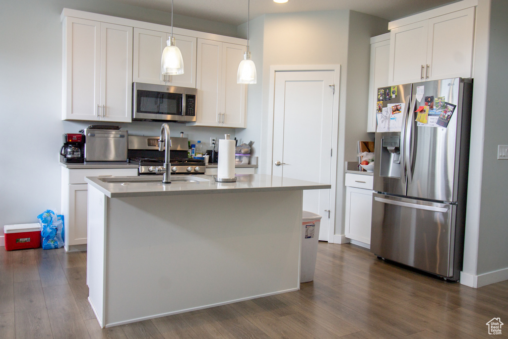 Kitchen featuring stainless steel appliances, dark wood-type flooring, white cabinetry, hanging light fixtures, and recessed lighting