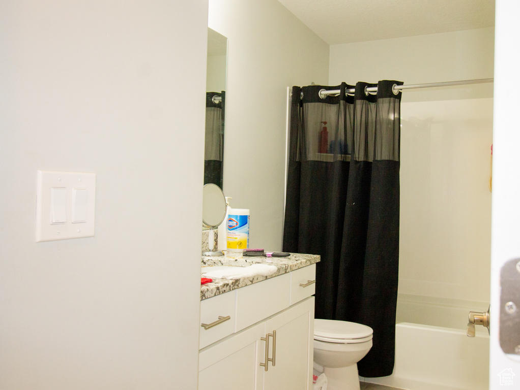 Bathroom featuring vanity, toilet, and shower / tub combo with curtain