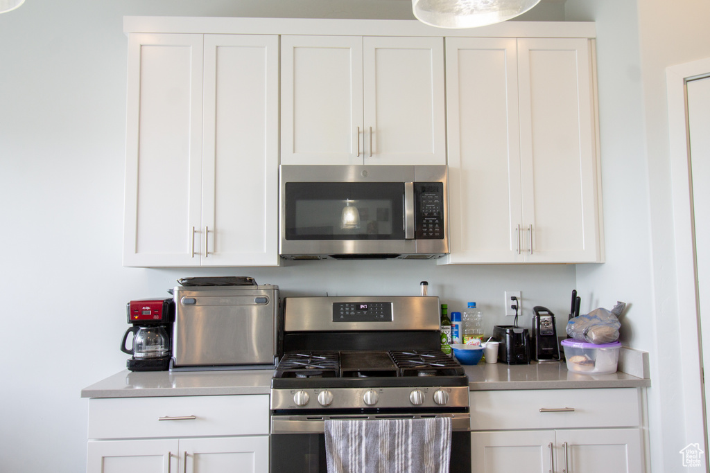 Kitchen with stainless steel appliances, light countertops, and white cabinetry