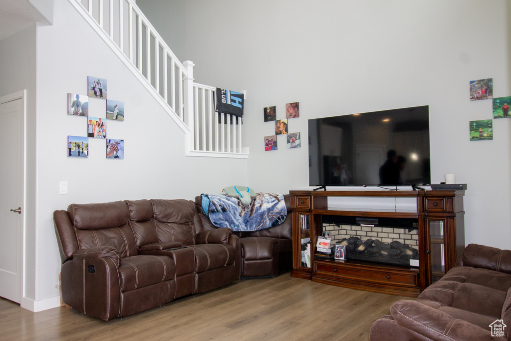 Living room with wood finished floors, a high ceiling, stairs, and baseboards