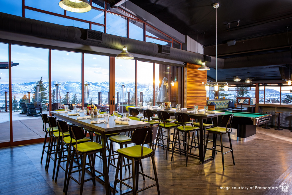 Dining area with a high ceiling, a mountain view, wood finished floors, a wall of windows, and billiards table