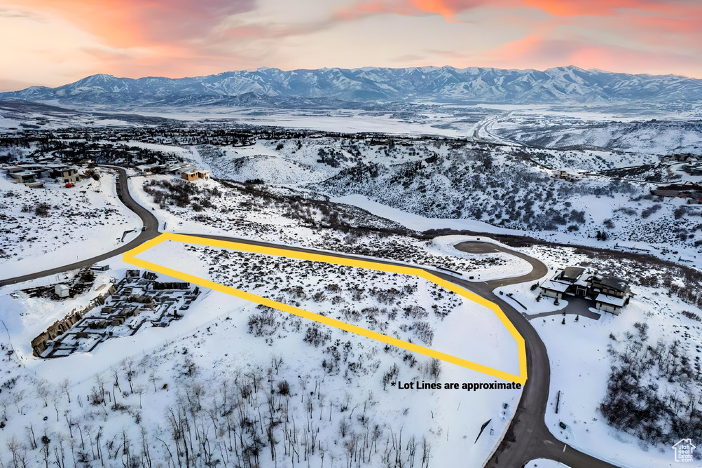 Snowy aerial view featuring a mountain view and property boundaries highlighted