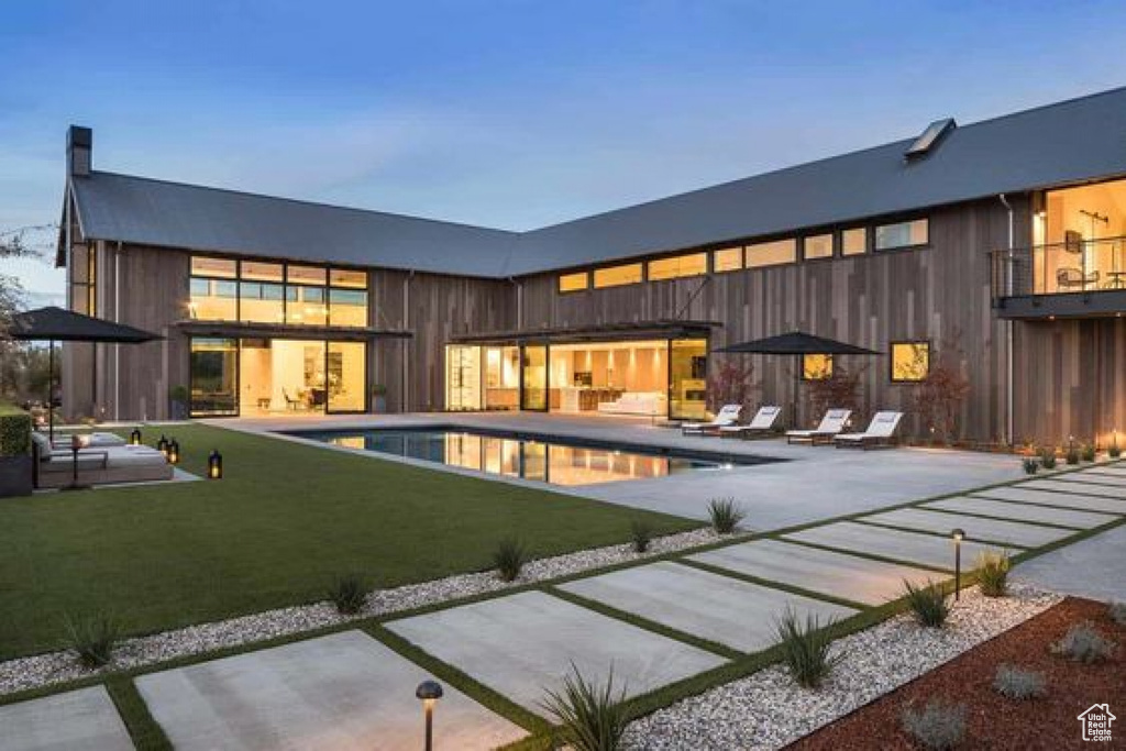 Rear view of house with a patio area, an outdoor pool, and a lawn