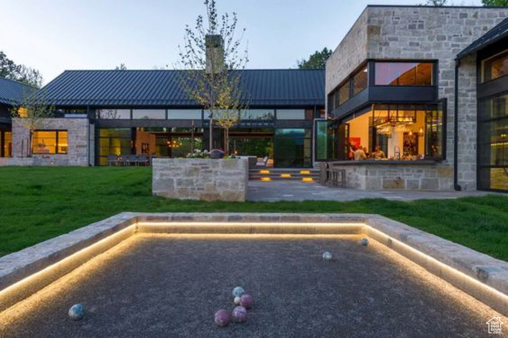 Back of property with a standing seam roof, stone siding, a chimney, and metal roof