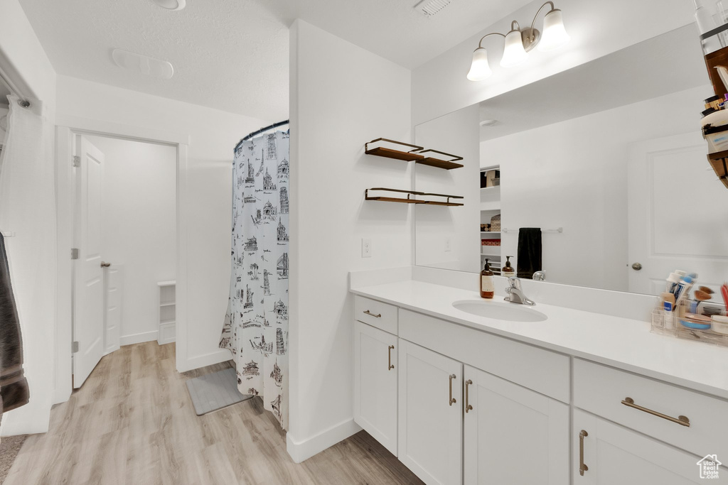 Full bathroom featuring wood finished floors, vanity, a shower with curtain, and baseboards